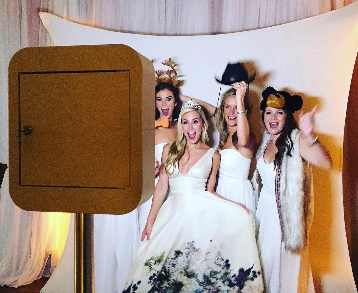 Bride and bridesmaids laughing with props at a Mr. Booth photo booth