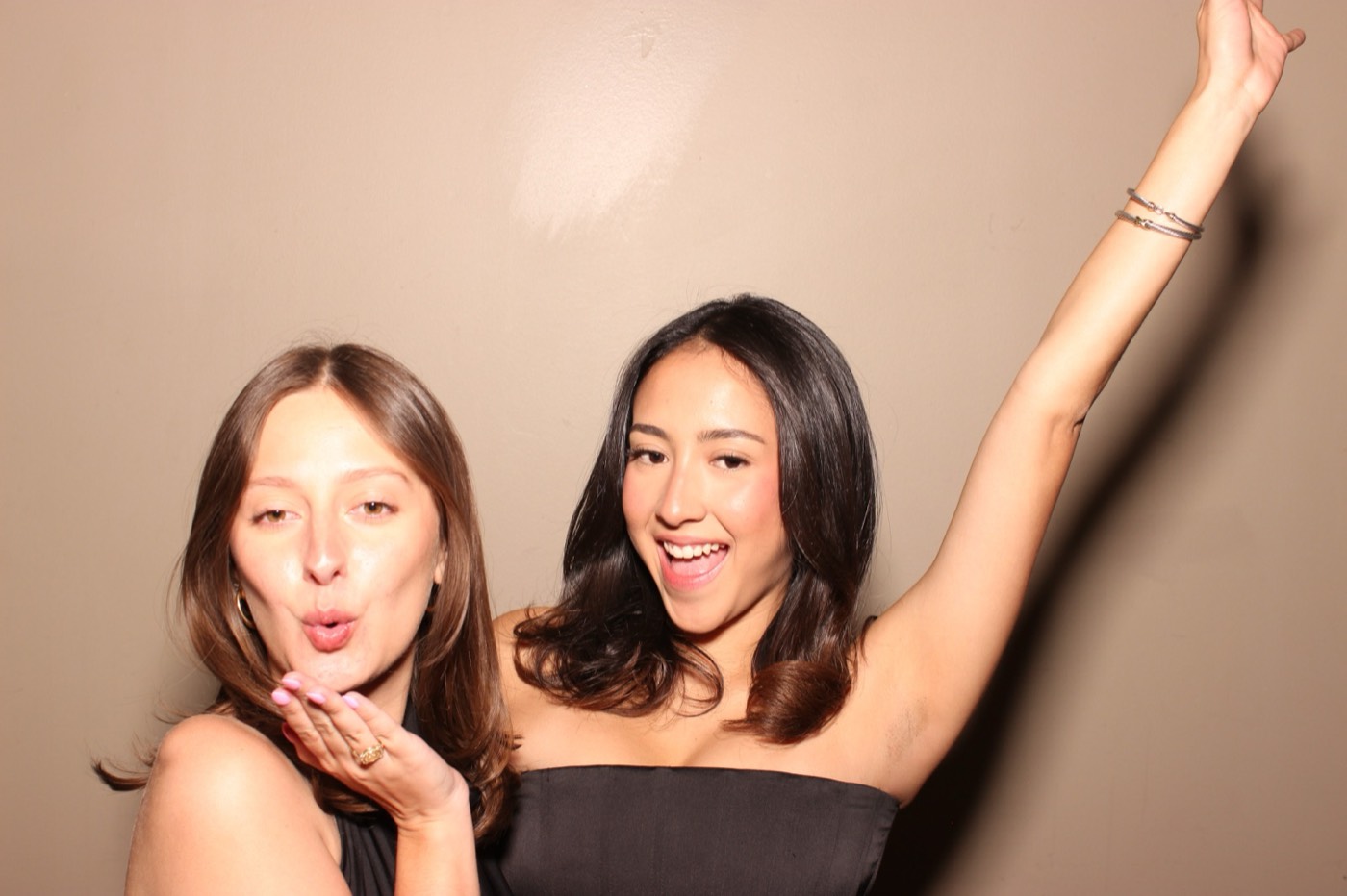 Two friends blowing a kiss with an arm in the air at a formal dance in San Antonio