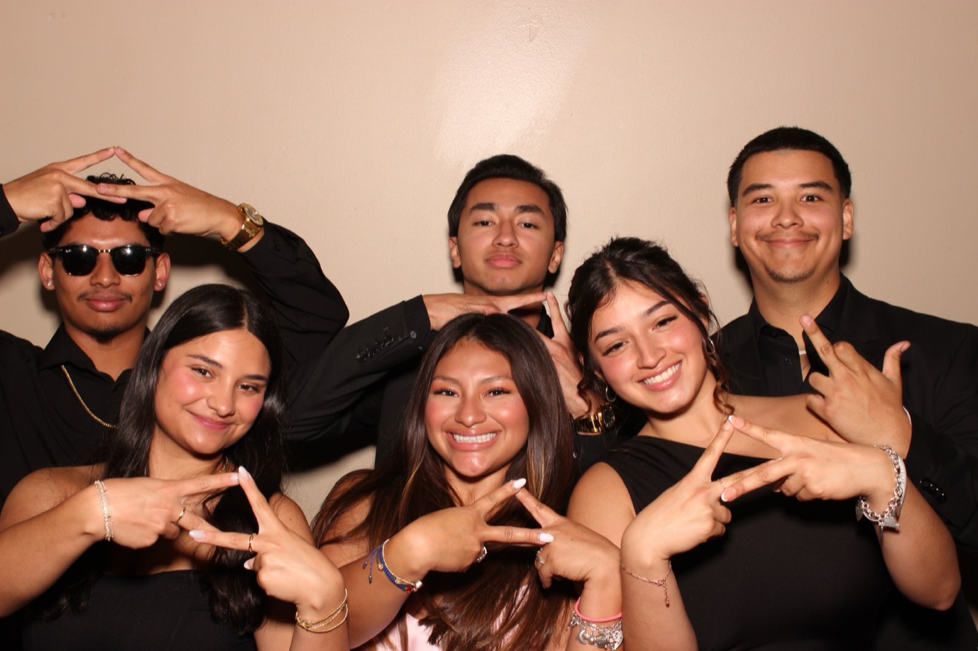 Friends in black and red throwing hand signs at a formal dance in San Antonio