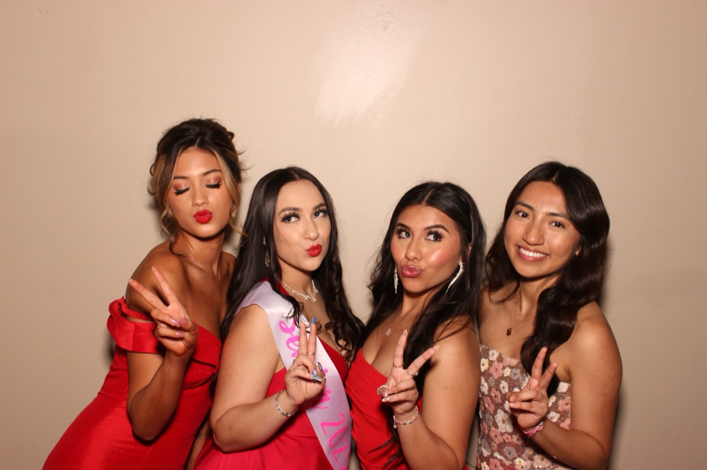Four friends in red dresses, one wearing a sash at a formal dance in San Antonio