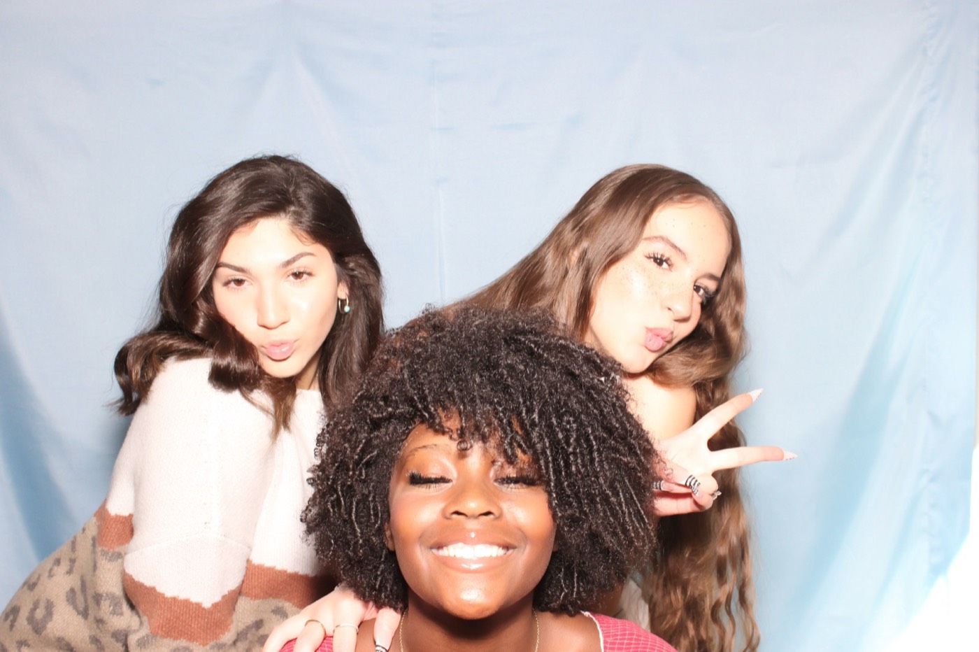 Three friends posing close together at a house party in San Antonio