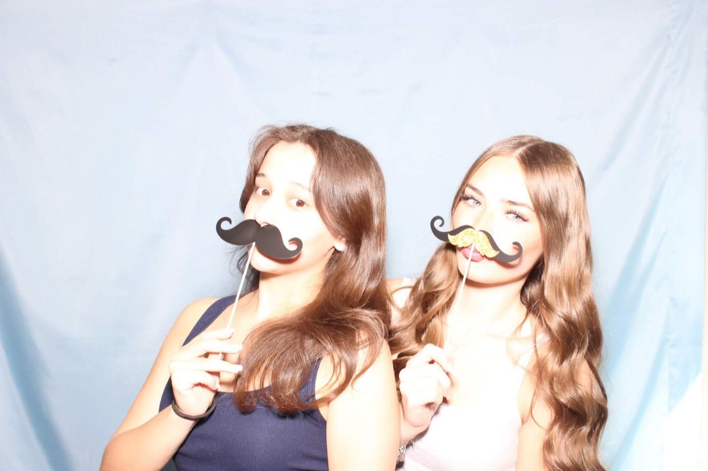 Two friends with mustache props at a house party in San Antonio