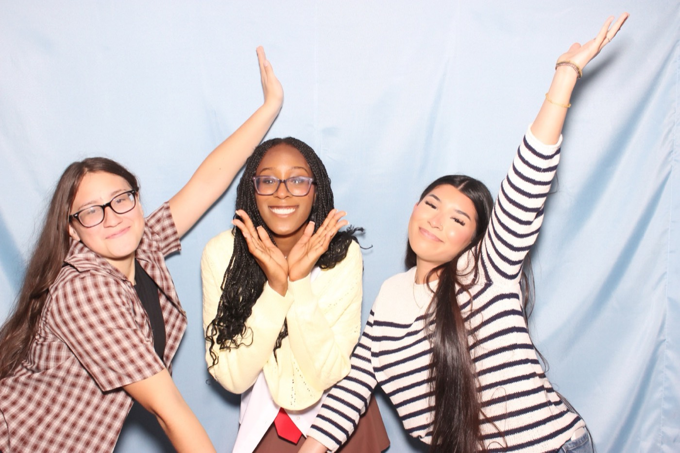 Three friends throwing their arms up at a house party in San Antonio