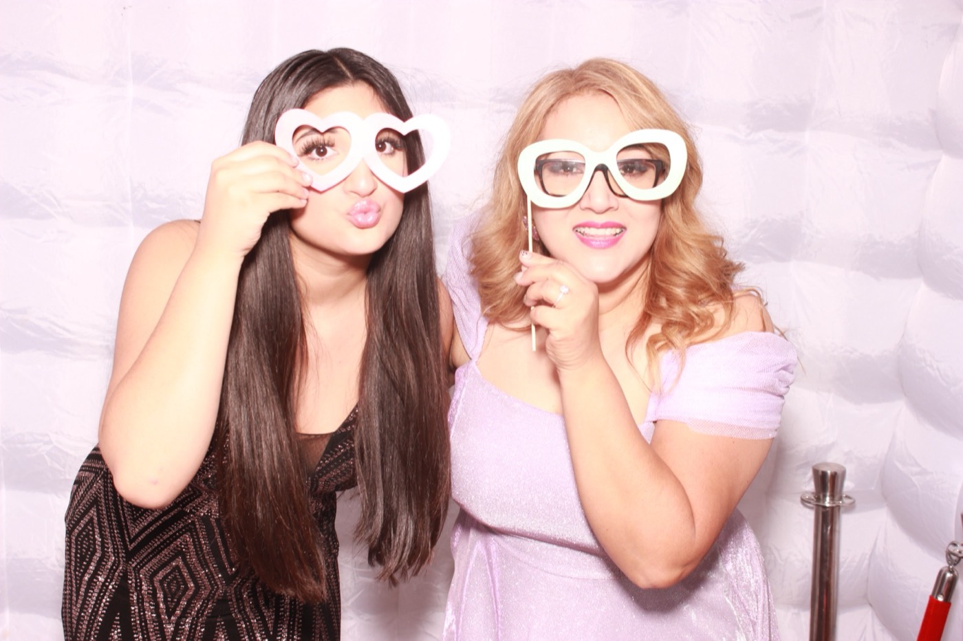 Two guests holding heart-shaped glasses props at a quince party in San Antonio