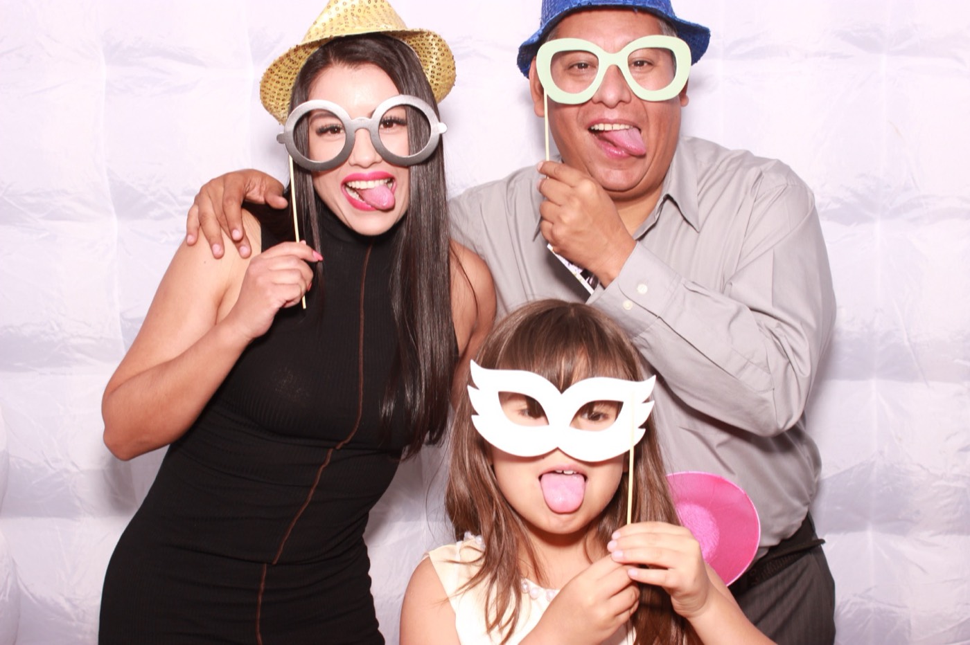 A dad and his daughters with mask and glasses props at a quince party in San Antonio
