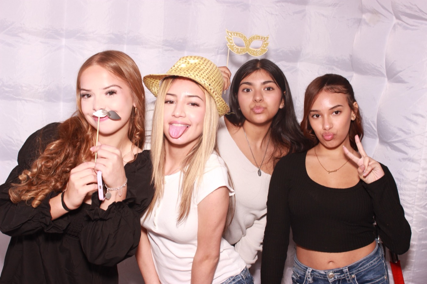 Four friends with hat and tongue-out props at a quince party in San Antonio