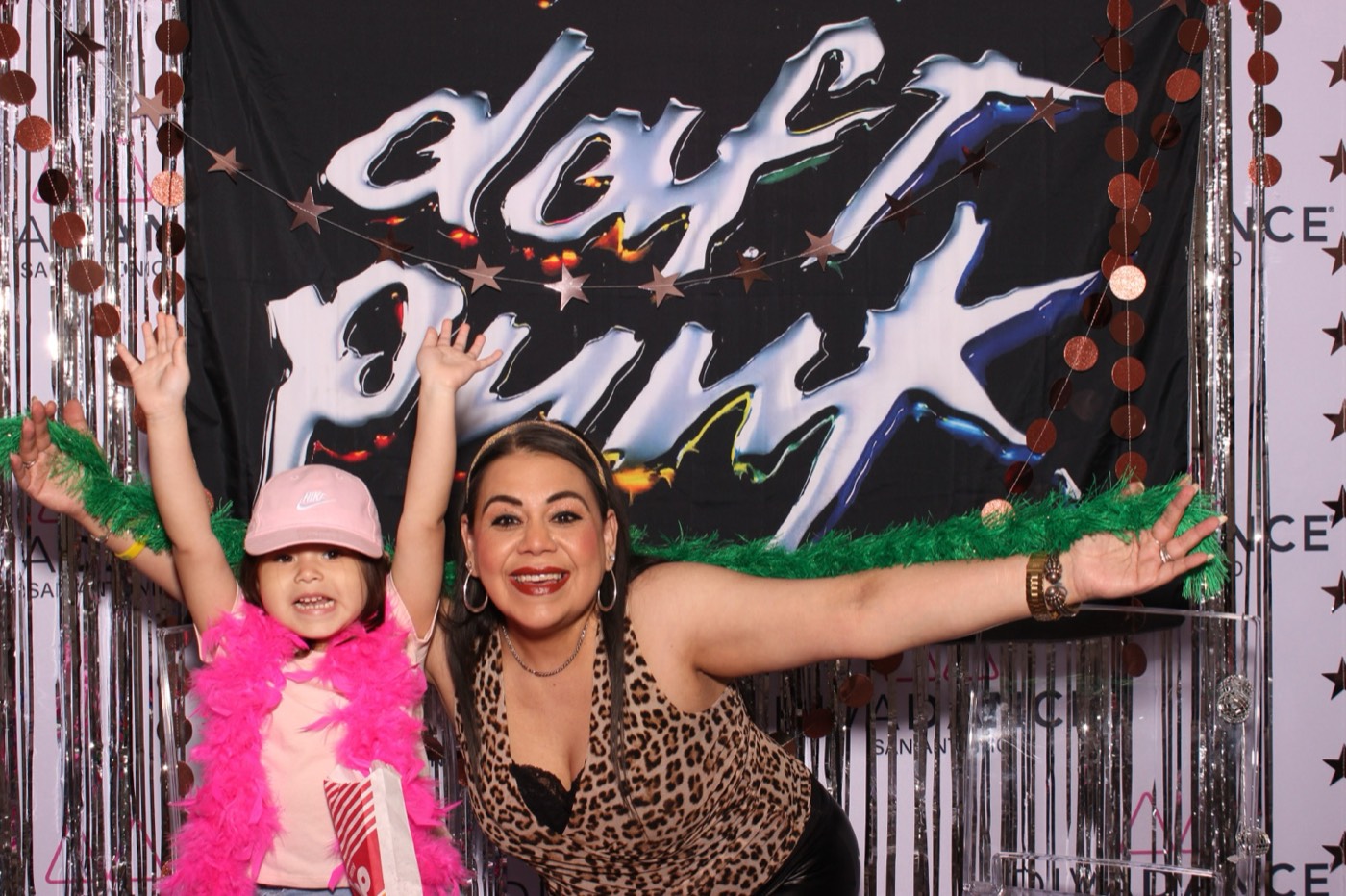A little girl and her mom cheering in feather boas at a Daft Punk themed birthday party