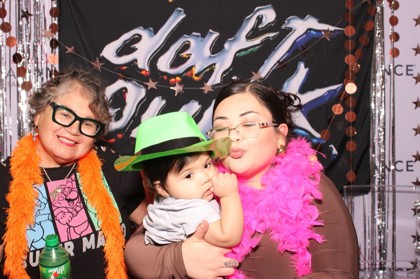 A grandma holding a toddler in a green hat at a Daft Punk themed birthday party
