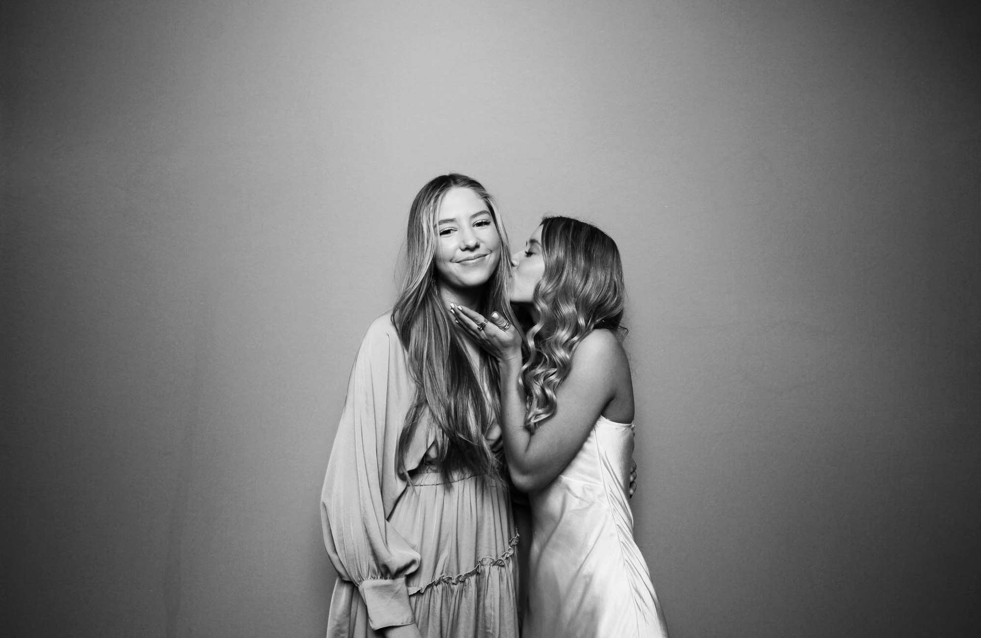 Two women sharing a joyful moment in a black and white photo booth picture by Mr Booth San Antonio.